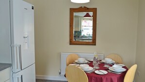 A dining area with a table set for four, a white refrigerator, and a mirror above the table. - 2 bedroom accommodation in Llanrhaeadr, near Denbigh (Llanrhaeadr, near Denbigh)