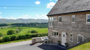 A two-story house with a stone facade, a balcony, and a view of green fields and hills. - 2 bedroom accommodation in Llanrhaeadr, near Denbigh (Llanrhaeadr, near Denbigh)
