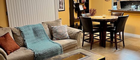 A living room with a sofa, coffee table, and dining area with chairs and a table.