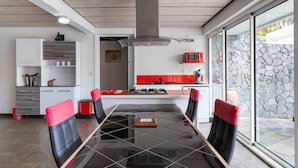 Une cuisine moderne avec une table à manger en verre, des appareils électroménagers rouges et un mur en pierre.
