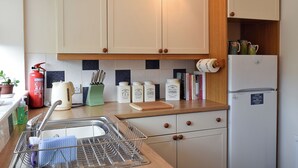 A kitchen with a sink, dishwasher, and a refrigerator. There are cabinets above the counter, and a fire extinguisher is visible on the left. - 2 bedroom accommodation in Leyburn (Leyburn)