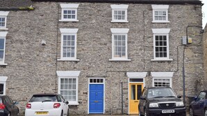 A stone building with multiple windows and doors, parked cars, and a visible number plate. - 2 bedroom accommodation in Leyburn (Leyburn)