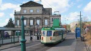 A tram at a station with a historic building in the background. - Spring Cottage-E3846 (Kirk Ireton, near Matlock)