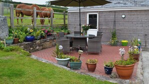 Un espace patio aménagé avec une table et des chaises, entouré de plantes en pot et d’une clôture en bois.