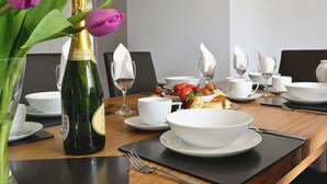 A dining table set with white dishes, a bottle of champagne, and a vase of pink tulips. - 3 bedroom accommodation in Bittaford, near Ivybridge (Bittaford, near Ivybridge)