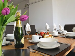 A dining table set with white dishes, a bottle of champagne, and a vase of pink tulips. - 3 bedroom accommodation in Bittaford, near Ivybridge (Bittaford, near Ivybridge)