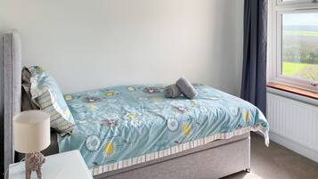 A bedroom with a bed, a nightstand, a lamp, and a window with curtains.