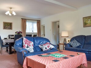 A living room with two blue leather sofas, a dining table, and a chandelier.