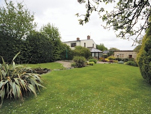 A well-maintained garden with a house, a pond, and various plants.