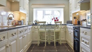 Een keuken met witte kasten, een zwarte kookplaat en een raam met uitzicht.
