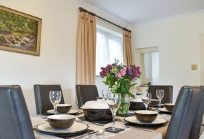 A dining table set with plates, bowls, and wine glasses, surrounded by chairs.