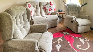Ein Wohnzimmer mit einer Couch, Sesseln, einem kleinen Tisch und einem dekorativen Teppich.