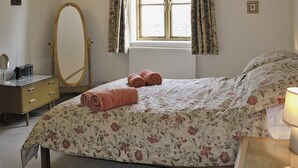 A bedroom with a bed, a dresser, a mirror, and a window with curtains. - 1 bedroom accommodation in Ebrington, near Chipping Campden (Ebrington, near Chipping Campden)