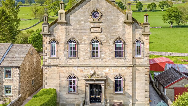 A stone building with a central entrance, multiple windows, and a clock tower.