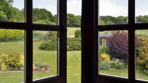 A view through a window with a garden in the foreground and a gazebo in the background.
