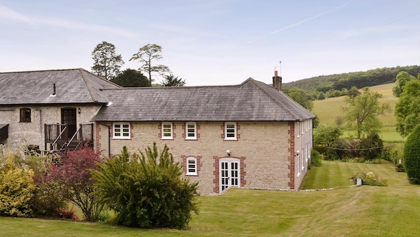 A stone house with a sloped roof, a front door, and a small porch.