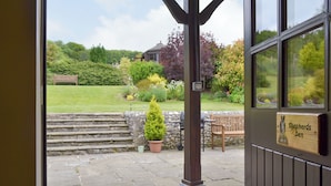 A stone staircase leading to a garden area with a wooden bench and a sign reading "Shepherds Den".