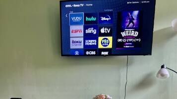 A television mounted on a wall displaying various streaming services and a movie poster.