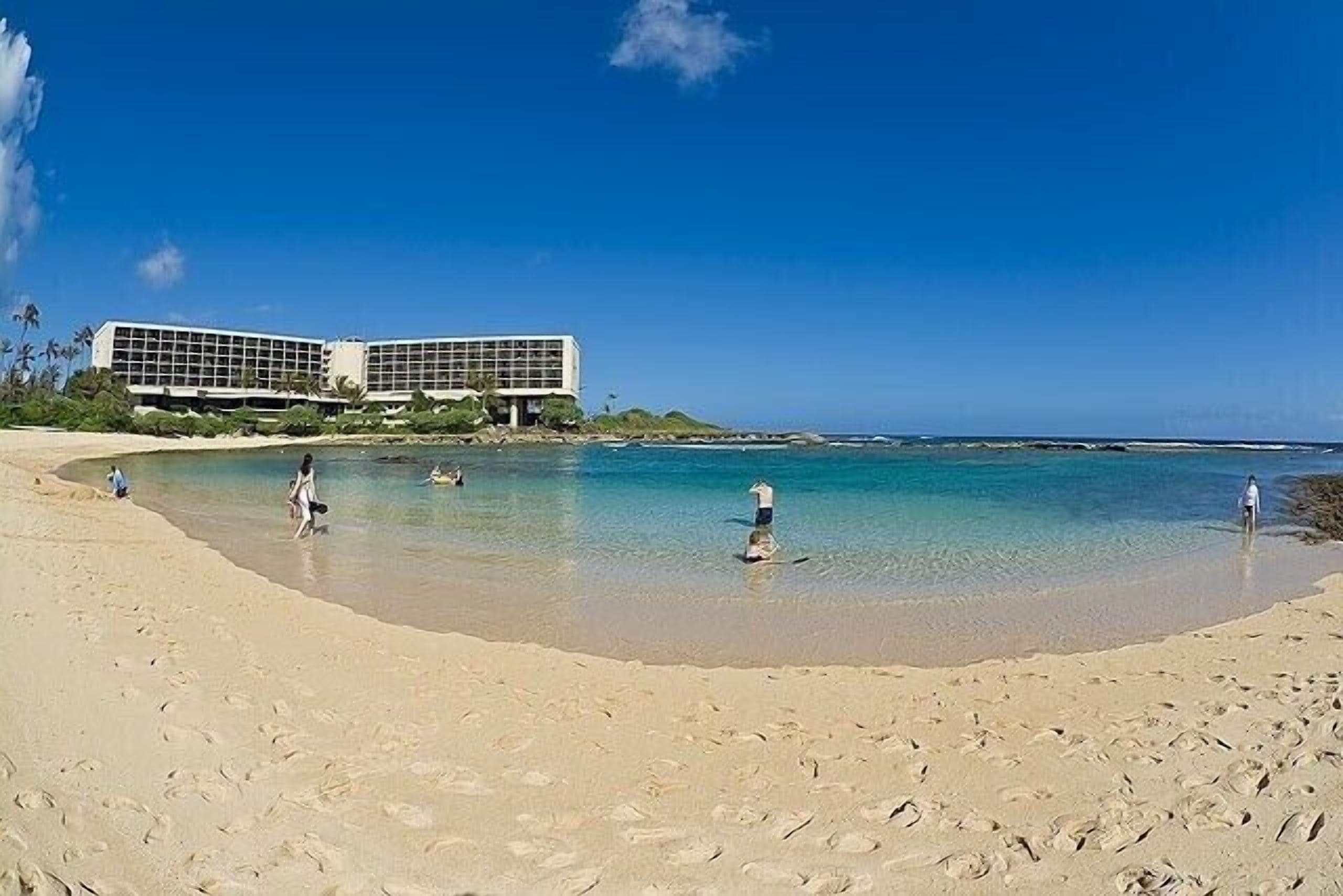 A beach with a modern building in the background.