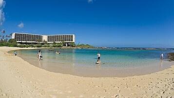 A beach with a modern building in the background.