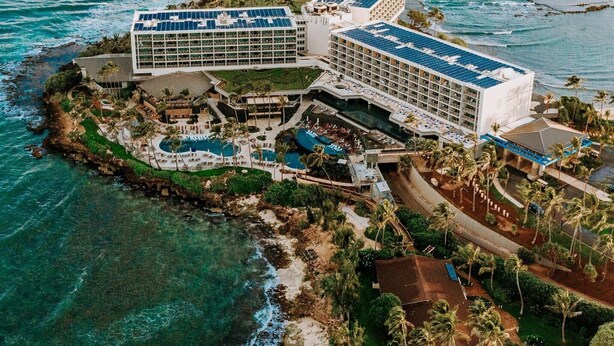 An aerial view of a resort with multiple buildings, a large pool area, and a beachfront location.