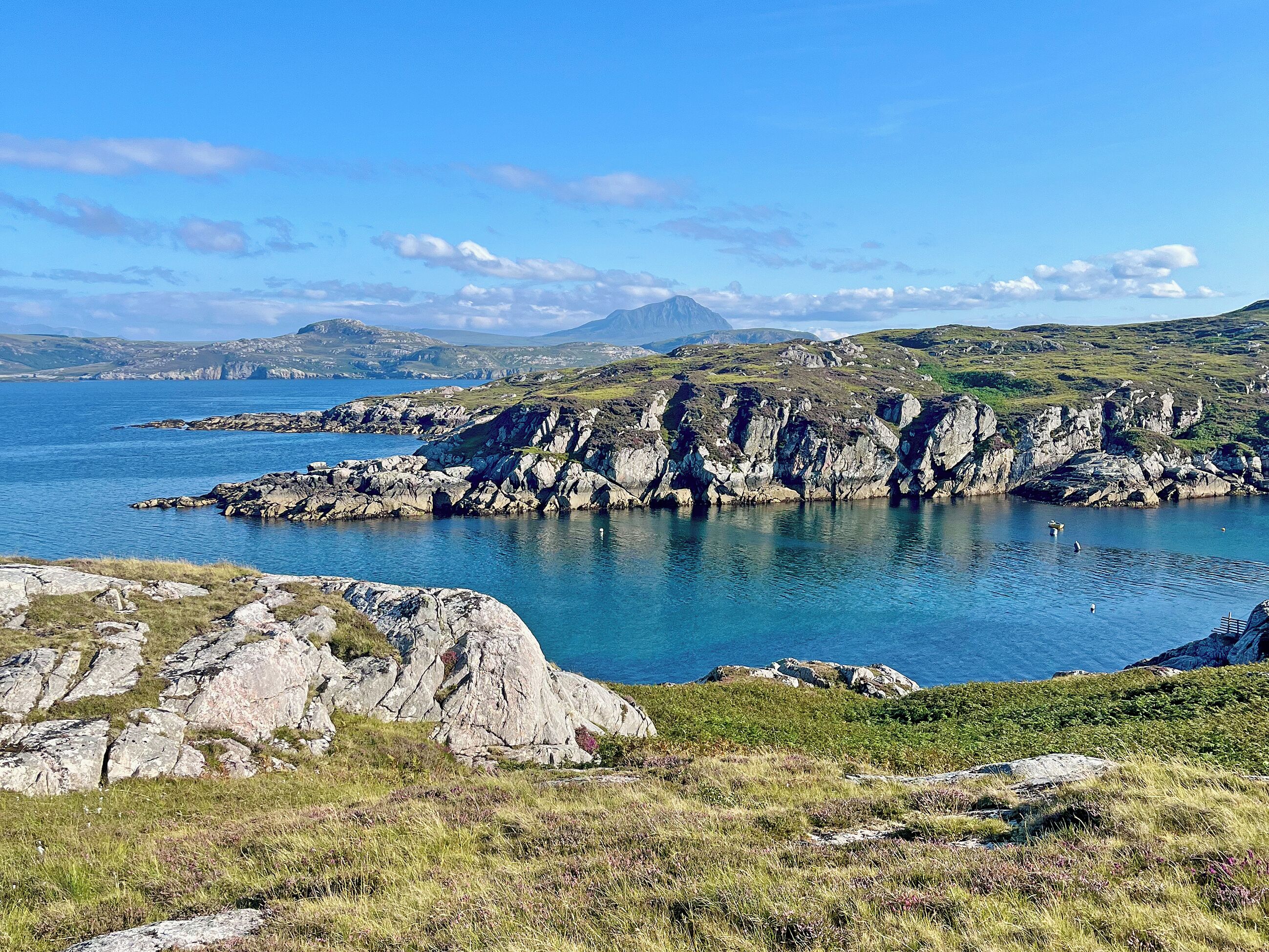 A coastal landscape with rocky terrain and a clear view of the sea.