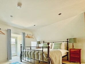 A bedroom with a bed, bedside tables, a hanging coat rack, and a door leading outside. - 4 bedroom accommodation in Rispond, near Durness (Rispond, near Durness)