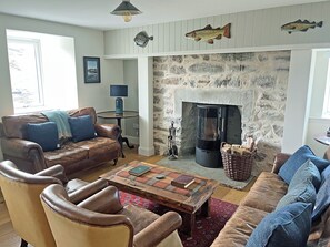 A living room with leather sofas, a fireplace, and decorative fish wall art. - 4 bedroom accommodation in Rispond, near Durness (Rispond, near Durness)