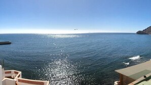 En fri utsikt över havet från ett båtdäck, med en klippig kustlinje i fjärran.