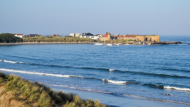 A coastal town with a sandy beach, a row of houses, and a fortified structure by the sea. - 2 bedroom accommodation in Beadnell, near Seahouses (Beadnell, near Seahouses)