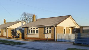 A two-story house with a brick facade, a pitched roof, and a front porch. - 2 bedroom accommodation in Beadnell, near Seahouses (Beadnell, near Seahouses)