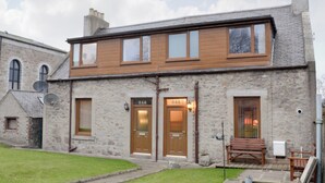 A stone building with two wooden doors, numbered 348 and 346, and a bench outside. - 1 bedroom accommodation in Aberdeen (Aberdeen)