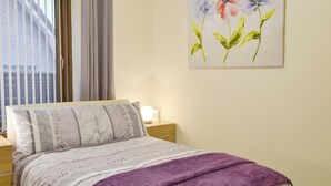 A bedroom with a bed, a nightstand, a lamp, and a window with curtains. - 1 bedroom accommodation in Aberdeen (Aberdeen)
