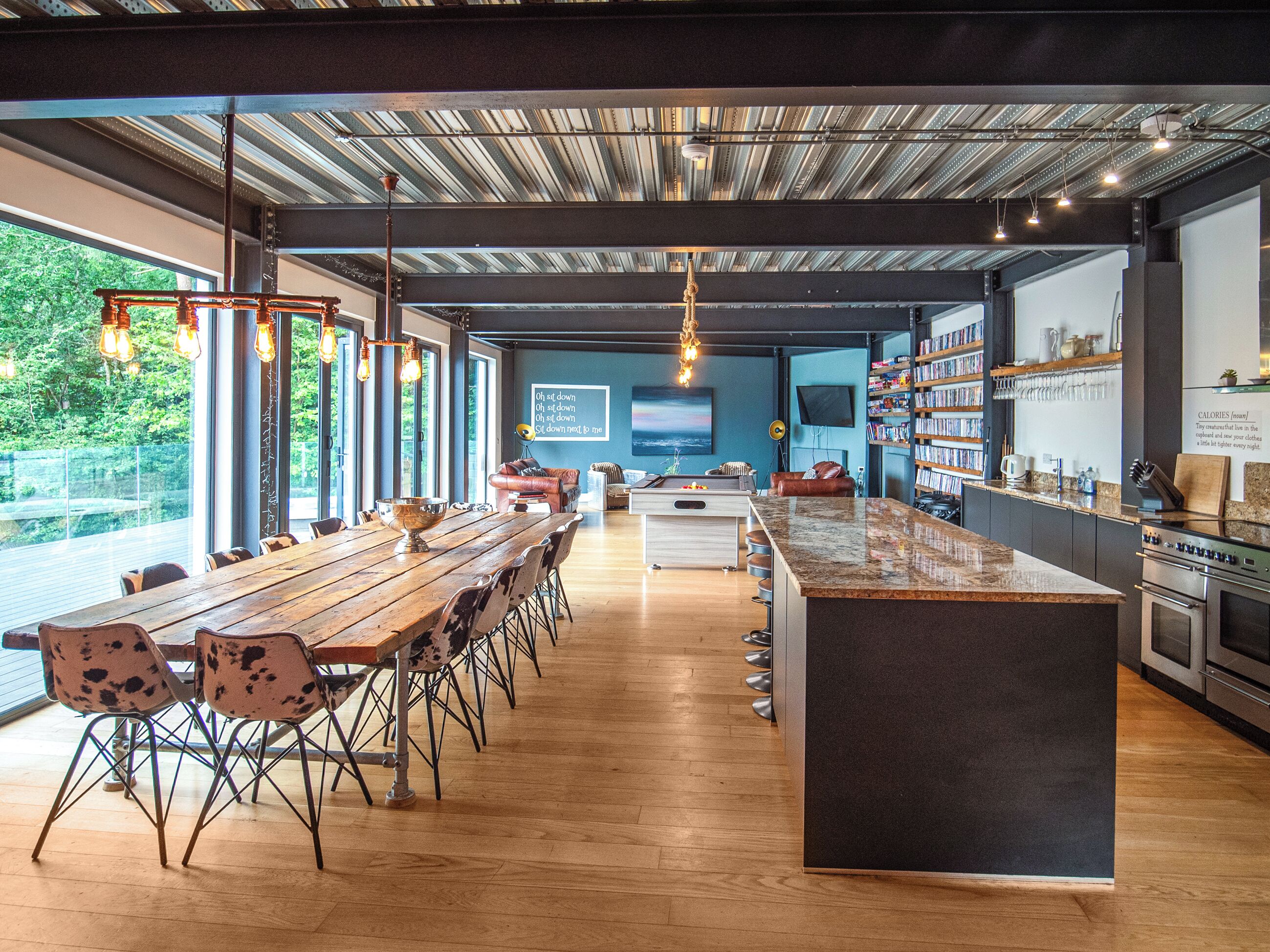 Een moderne keuken met een groot schiereiland, een houten eettafel en stoelen.
