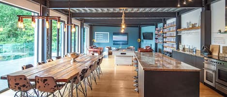 A modern kitchen with a large island, wooden dining table, and chairs.