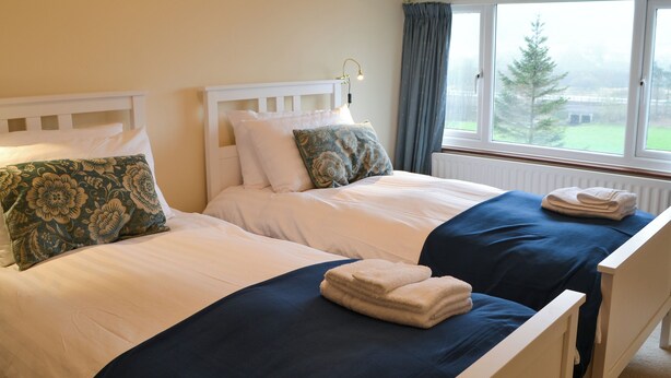 A double bed with white and blue bedding, a matching pillow, and a folded towel on the bed. - 2 bedroom accommodation in Bassenthwaite, near Keswick (Bassenthwaite, near Keswick)