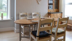 A dining area with a round wooden table, four chairs, and a cabinet with glass doors. - 2 bedroom accommodation in Bassenthwaite, near Keswick (Bassenthwaite, near Keswick)