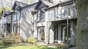 A two-story house with a balcony, large windows, and a well-maintained garden. - An apartment situated in mature woodlands just 3 miles from Ambleside. (Skelwith Bridge, Ambleside)