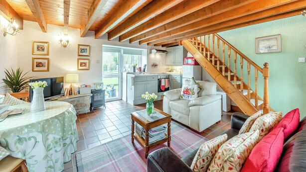 A spacious living room with a wooden ceiling, a dining area with a round table, and a kitchen visible through an open door. - 1 bedroom accommodation in Gowerton, Gower (Gowerton, Gower)
