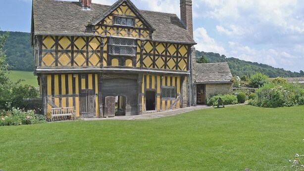 A traditional half-timbered house with a stone chimney, a wooden bench, and a well-maintained lawn. - 3 bedroom accommodation in Broome Chatwall, near Church Stretton (Broome Chatwall, near Church Stretton)
