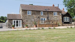 A stone house with a tiled roof, a wooden deck, and a fenced garden area. - 3 bedroom accommodation in Broome Chatwall, near Church Stretton (Broome Chatwall, near Church Stretton)