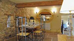 A dining area with a stone wall, wooden beams, a round mirror, and a table set for four. - 3 bedroom accommodation in Broome Chatwall, near Church Stretton (Broome Chatwall, near Church Stretton)