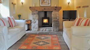 A cozy living room with a stone fireplace, white sofas, and a television. - 3 bedroom accommodation in Broome Chatwall, near Church Stretton (Broome Chatwall, near Church Stretton)