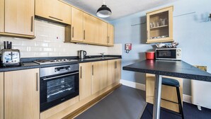 A kitchen with wooden cabinets, a gas stove, a microwave, a toaster, and a red pot.