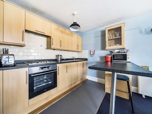 A kitchen with wooden cabinets, a gas stove, a microwave, a toaster, and a red pot.