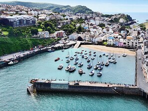 A coastal town with a marina filled with boats, a sandy beach, and a mix of residential and commercial buildings.