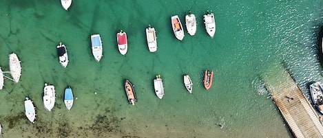 Luchtbeeld van een jachthaven met verschillende boten afgemeerd, een zandstrand en een houten pier.