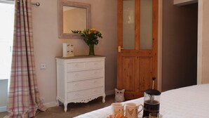 Un lit bien fait, avec des éléments pour le petit-déjeuner, une porte en bois, une commode et un miroir au mur.