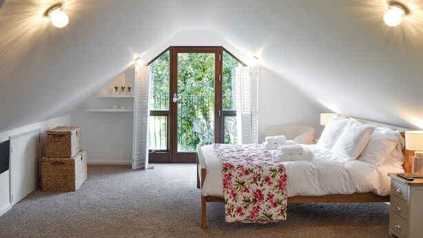 Une chambre à coucher avec un lit, une table de chevet et une vue sur la verdure.