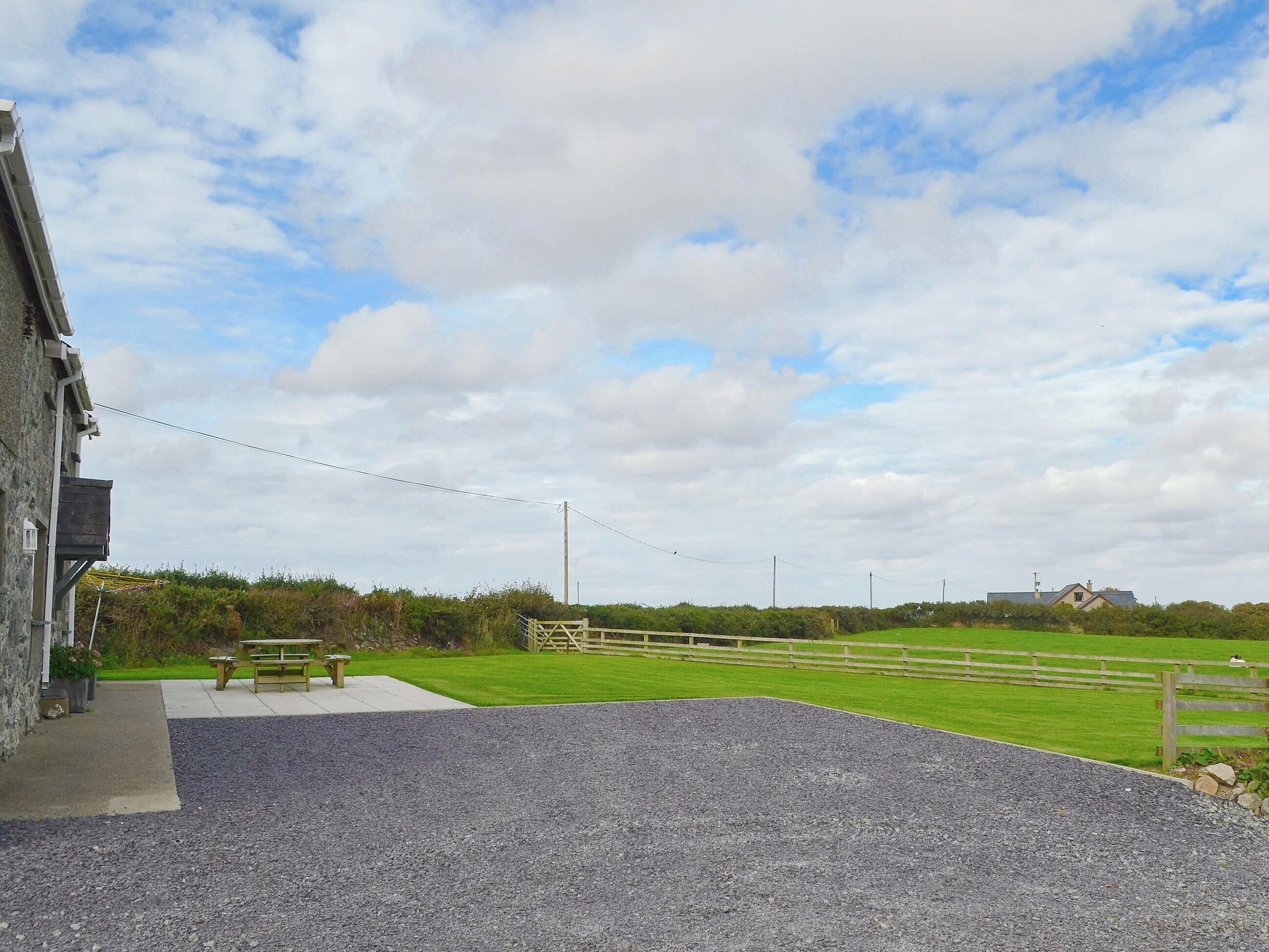 A gravel parking area with a picnic table and a building with a stone facade.